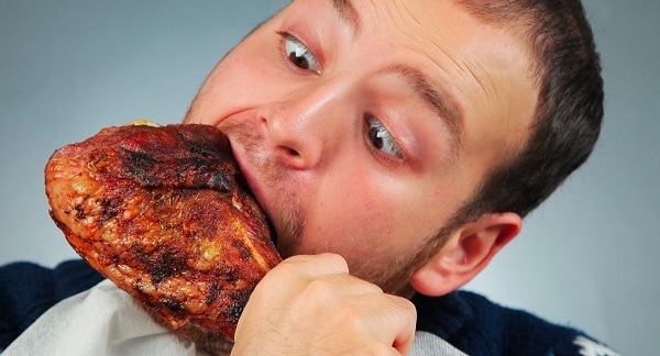 man pigging out and eating turkey leg